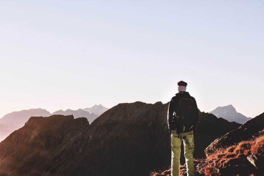 A walker looking across a mountain ridge in the evening light